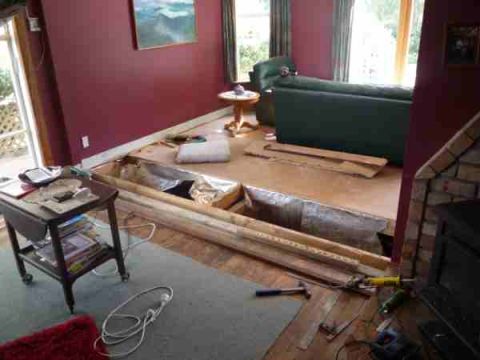 1969 Lincoln Continental - A room undergoing renovation shows exposed floor joists and construction materials alongside furniture and a fireplace.