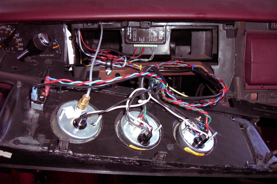 Back side of three aftermarket gauges being wired into a custom dash panel