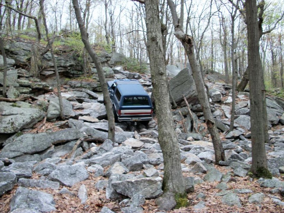 Blue SUV on rocky trail, 1980s body style