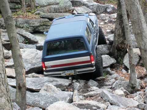 1986 Ford Bronco - This SUV is shown navigating a difficult rocky terrain, with its rear end visible.