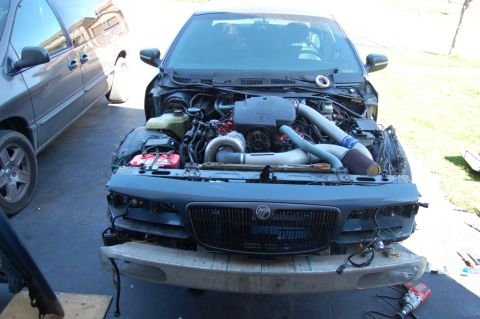 1985 Mercury Grand Marquis - The front of a 1985 Mercury Grand Marquis is shown with its engine exposed, revealing custom turbocharger modifications.
