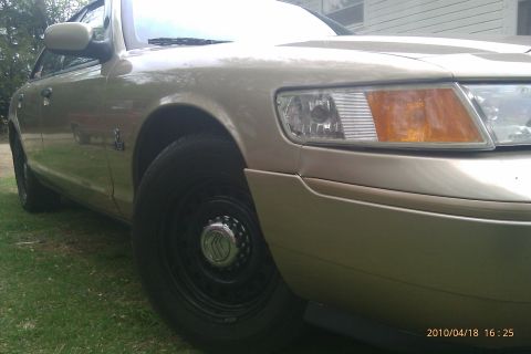 2000 Mercury Grand Marquis - Front quarter view of a gold 2000 Mercury Grand Marquis parked on grass.