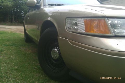 2000 Mercury Grand Marquis - This gold sedan is parked on a grassy area, with trees in the background.