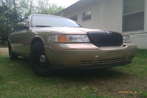 2000 Mercury Grand Marquis - This 2000 Mercury Grand Marquis is seen from a 3/4 front angle, parked on grass in front of a house.