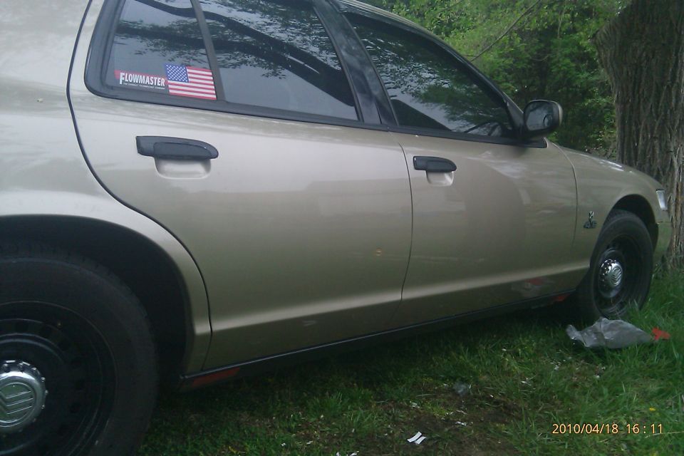 Tan 2000 Mercury Grand Marquis side view with Flowmaster sticker on rear window