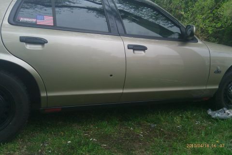 2000 Mercury Grand Marquis - This sedan has a bullet hole in the driver's side door and an American flag sticker on the rear window.