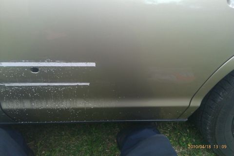 2000 Mercury Grand Marquis - The side panel of a car shows where trim pieces were removed, leaving holes and some paint damage.