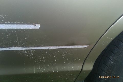 2000 Mercury Grand Marquis - Side view of a gold car door with water spots and damaged trim.