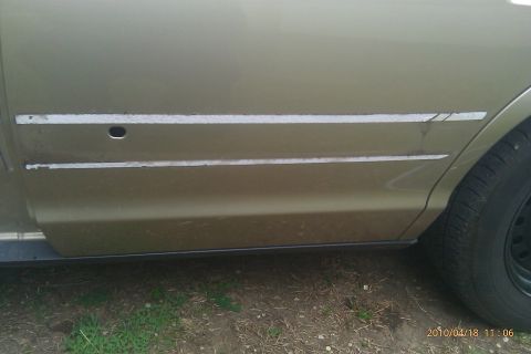 2000 Mercury Grand Marquis - Side view of a gold car's door panel, showing damage to the trim strips.