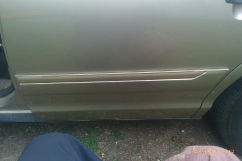 2000 Mercury Grand Marquis - Side view of gold car door trim with a chrome accent strip.