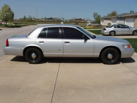 2000 Mercury Grand Marquis - A silver sedan is parked in a suburban driveway on a sunny day.
