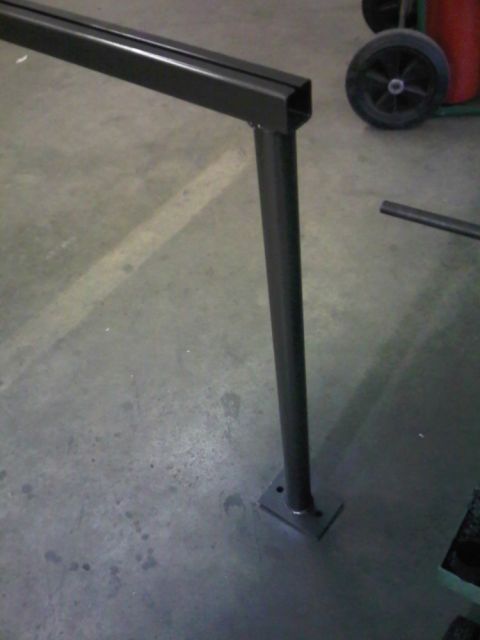 1996 Ford Bronco - A metal railing post stands on a concrete floor, with a wheel and part of a red object visible in the background.