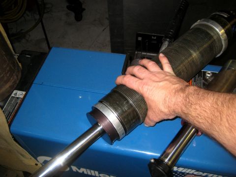 1996 Ford Bronco - Shock absorber assembly with bellows being held over a blue Miller welding machine.
