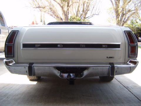 1973 Ford Ranchero - The rear of a light-colored Ford Ranchero pickup truck is shown, a chrome bumper and the Ford logo.