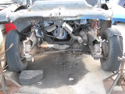 1954 Ford F-100 - The front end of a 1954 Ford F-100 pickup truck is shown, with the engine and suspension components visible as it sits in a repair shop.