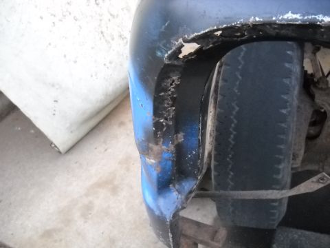 1954 Ford F-100 - The wheel well of a blue vehicle shows significant rust and damage.