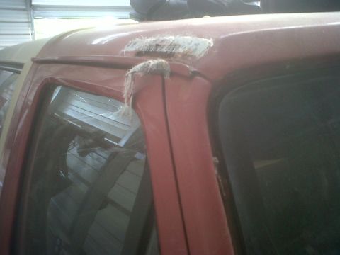 1989 Ford Bronco - Close-up of a red SUV's door frame showing a poorly done fiberglass repair patch with visible fibers.