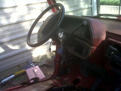 1989 Ford Bronco - Interior view of a red vehicle, showing the steering wheel and dashboard area.