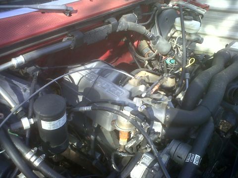 1989 Ford Bronco - Close-up view of an engine bay, showing various hoses, the intake manifold, and other engine parts.