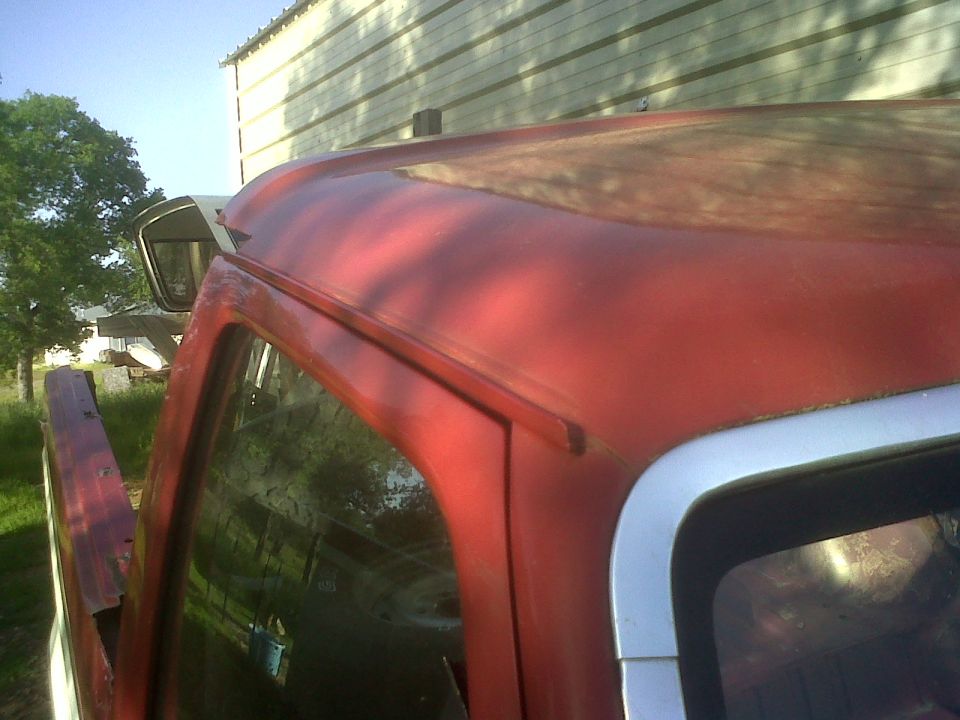 Red truck cab roof with weathered paint and chrome trim around window