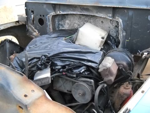1954 Ford F-100 - Engine bay of a vehicle, partially covered and in disarray, with visible engine components and a brake booster.