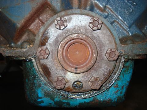 1979 Ford Bronco - A close-up view of a rusty engine component with visible bolts and a circular opening.