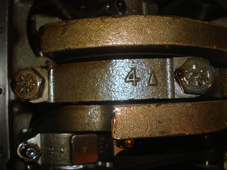 Close-up of engine crankshaft bearing caps with some stamped numbers