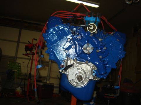 1979 Ford Bronco - A blue painted V8 engine with red spark plug wires is shown, mounted on an orange stand.