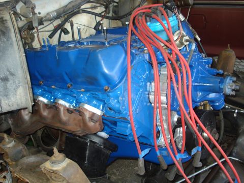 1979 Ford Bronco - The engine bay shows a blue V8 engine with prominent red spark plug wires and exhaust manifolds.