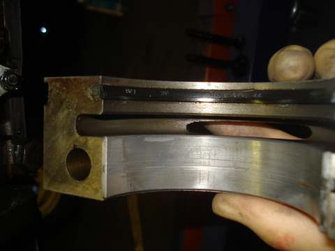 1979 Ford Bronco - A hand holds up two curved rear main seal halves side by side under shop light, showing the black rubber sealing lip on one and the polishe…