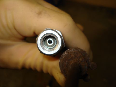 1979 Ford Bronco - A close-up view of a metal brake line fitting, with a rusty cap visible next to it.