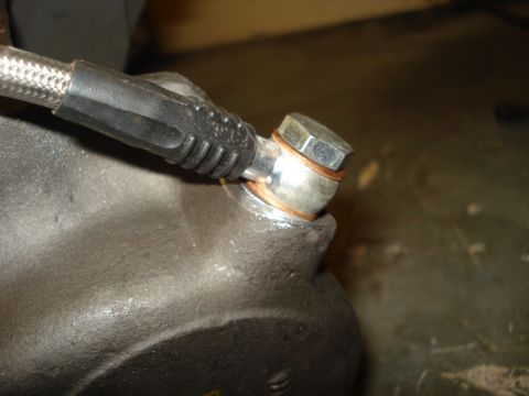 1979 Ford Bronco - Close-up view of a brake caliper showing the banjo bolt connection for the brake line, secured with copper crush washers.