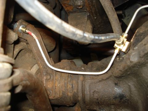 1979 Ford Bronco - Close-up view of brake lines and a proportioning valve attached to a vehicle's axle.