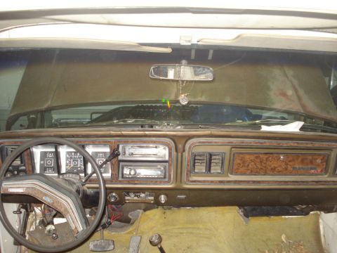 1979 Ford Bronco - Interior dashboard view of an older Ford truck showing the woodgrain-trimmed dash, steering wheel with Ford emblem, gauge cluster, center v…