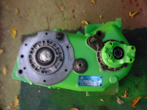 1979 Ford Bronco - New Process Gear transfer case painted bright green, lying on its side on a garage floor with the bare cast-aluminum front output bearing r…