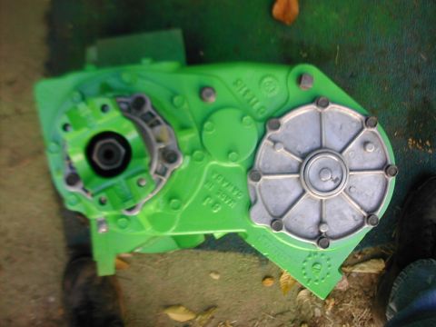 1979 Ford Bronco - Overhead shot of a lime-green painted cast-iron transfer case lying on the ground, showing its cast 'MADE IN CANADA' lettering, a bare alum…