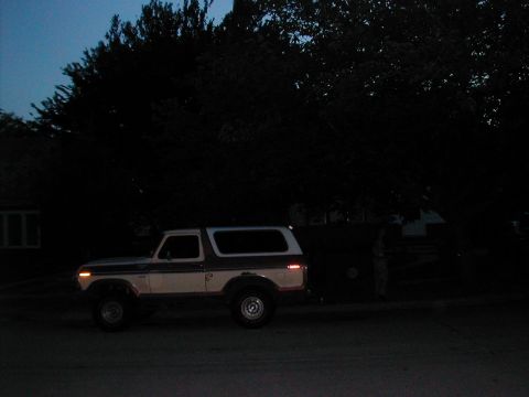 1979 Ford Bronco - Driver-side profile of a white full-size Ford Bronco with a removable hardtop, parked on a residential street at dusk with parking lights a…