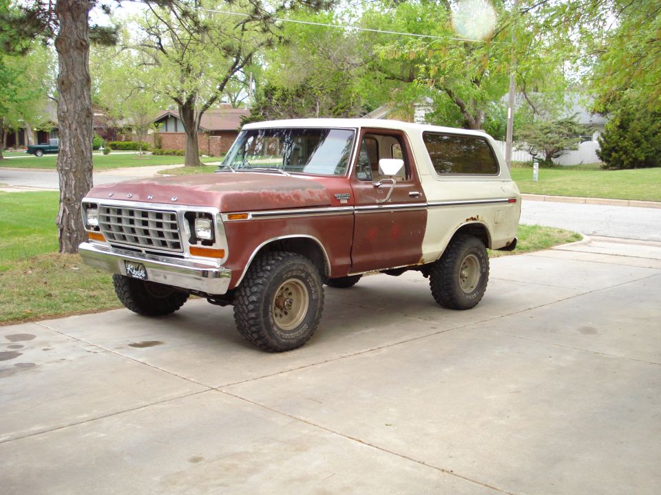 Lifted two-tone maroon and cream 1970s Ford Bronco on mud tires in driveway