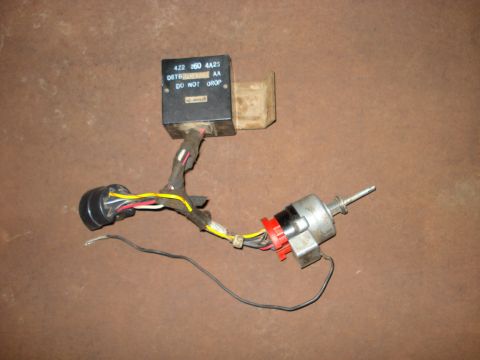 1979 Ford Bronco - A close-up shows an ignition switch and a relay module with associated wiring, laid out on a textured surface.