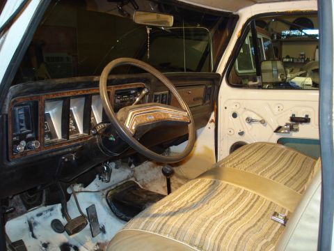 1979 Ford Bronco - The interior of a 1979 Ford Bronco shows its dashboard, steering wheel, and striped seats.