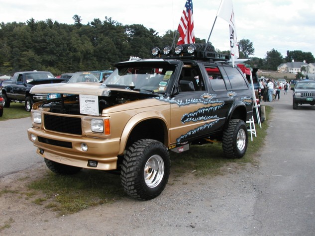 Gold and black lifted Chevy S-10 Blazer with light bar at outdoor car show