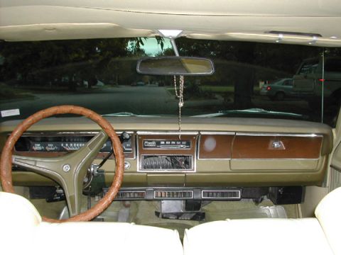 1971 Dodge Dart - The interior of a 1971 Dodge Dart shows a tan dashboard with wood grain accents and a brown steering wheel.