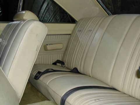 1971 Dodge Dart - The interior of a car shows tan vinyl seats with black seatbelts and door panel details.