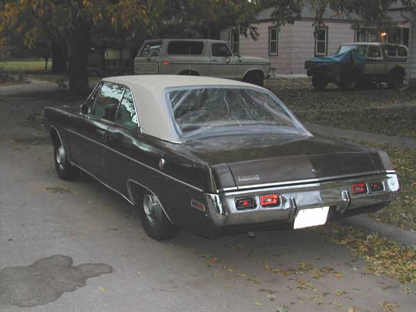 Rear of brown Dodge Dart hardtop with rear window removed and plastic sheeting taped over