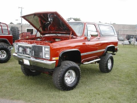 1994 Ford Bronco - This lifted SUV, likely from the 1980s, is displayed with its hood open, revealing the engine bay.