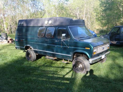 1981 Ford E350 - A modified van sits on a grassy area with trees in the background.