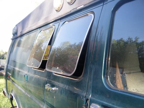 1981 Ford E350 - Side view of a green van with its windows cracked open, showing reflections of trees.