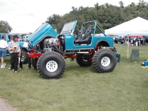 1994 Ford Bronco - Modified Jeep CJ on display with hood open, other vehicles and tents visible in the background.