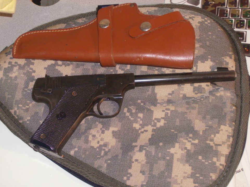 Blued semi-automatic pistol and brown leather holster on camo case