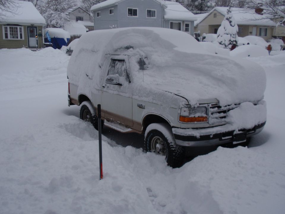 1996 Ford Bronco buried in snow, parked in a residential driveway